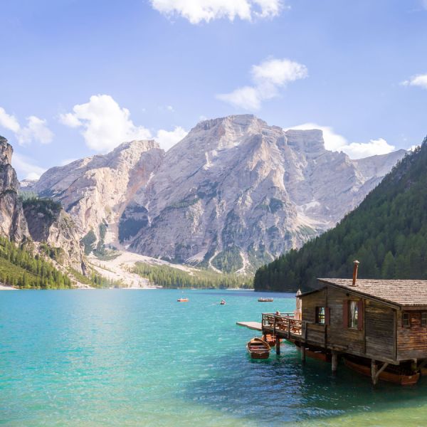 Wooden boathouse on turquoise Lake Braies with dramatic Dolomite mountain peaks and forest surroundings