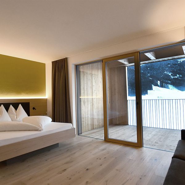 Modern hotel room interior at evening with balcony, snowy mountain view, and minimalist yellow accent lighting