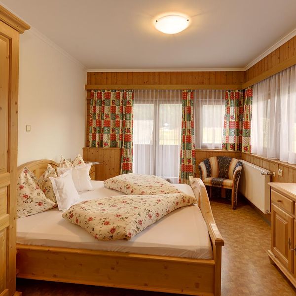Traditional Alpine hotel room with pine wood furniture, floral patterned bedding, and rustic country decor