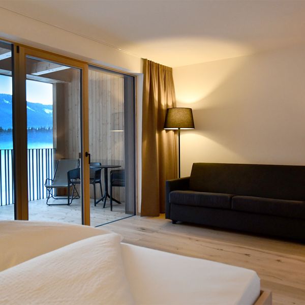 Spacious modern hotel room with evening mountain view through glass doors and contemporary minimalist design