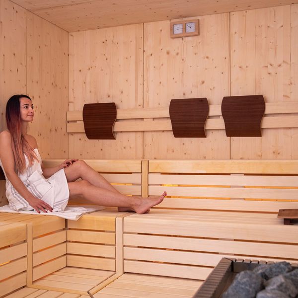 Woman relaxing in modern wooden sauna with LED-lit benches and natural pine construction
