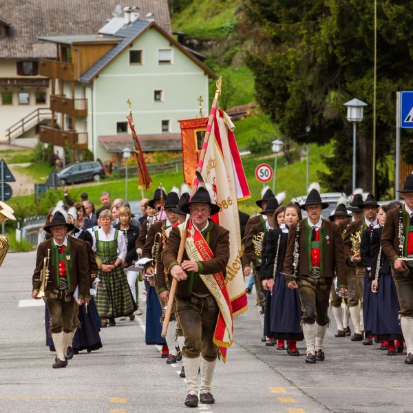 Traditional South Tyrolean folk parade with marching band in traditional costumes carrying regional flag through village