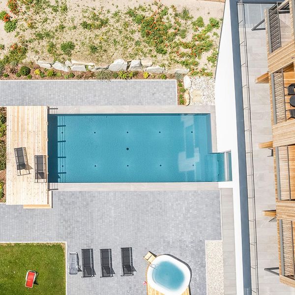 Aerial overhead view of modern hotel with rectangular outdoor pool, wooden deck terrace, and contemporary architectural design
